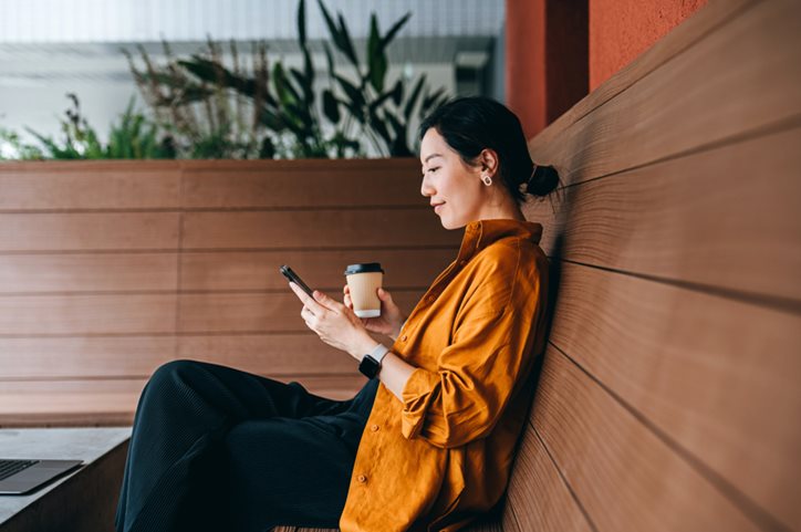 Young woman sitting down reading something on her phone