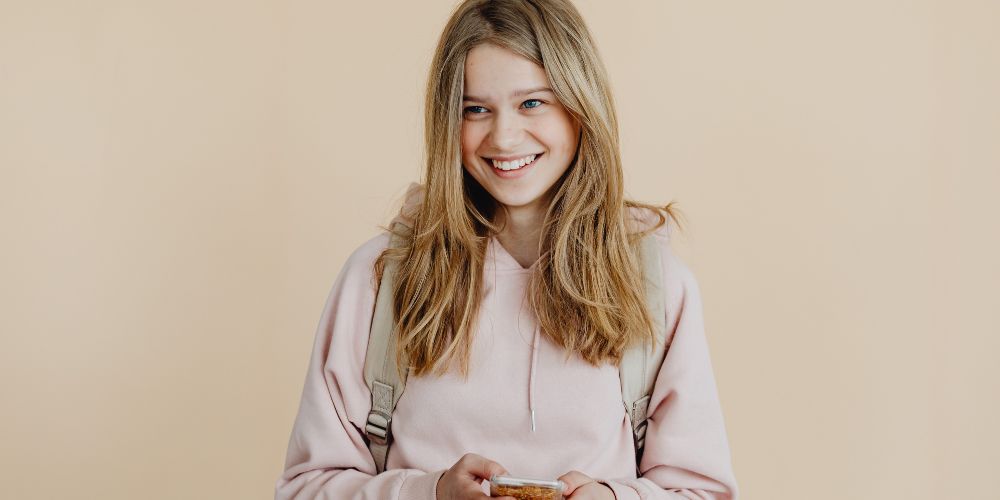 Young girl smiling holding her mobile phone