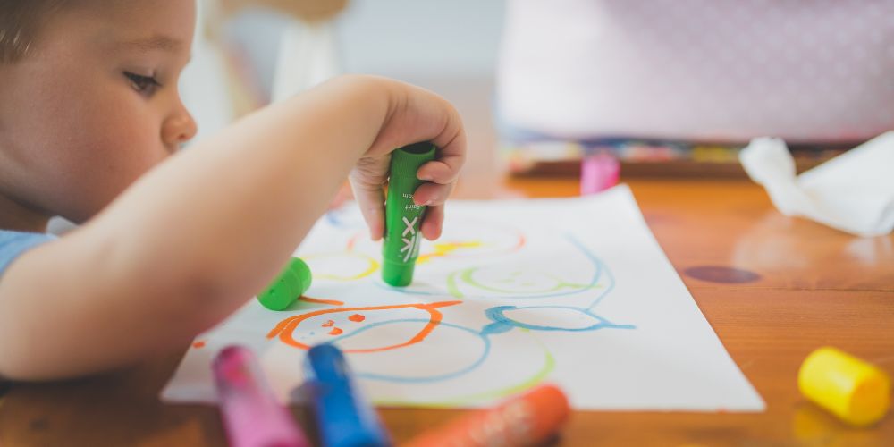 Young boy colouring with crayons