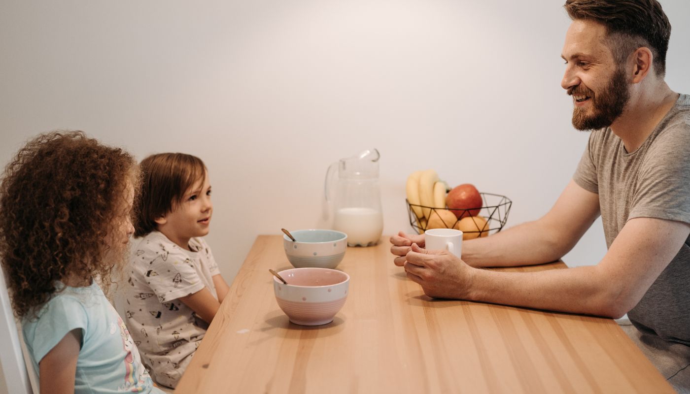 Father sitting at table talking to his two children.