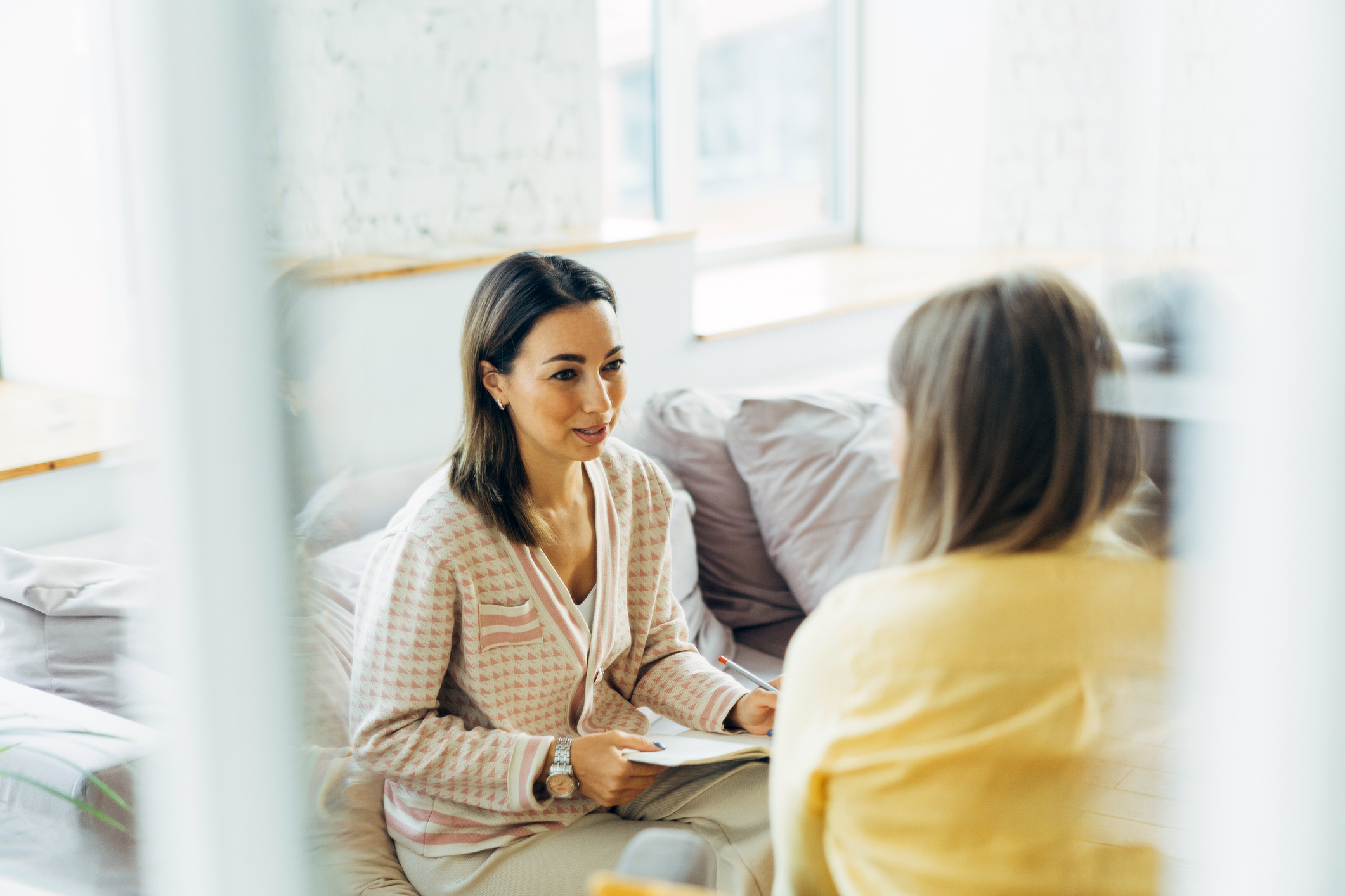 Woman with dark hair sitting facing another woman