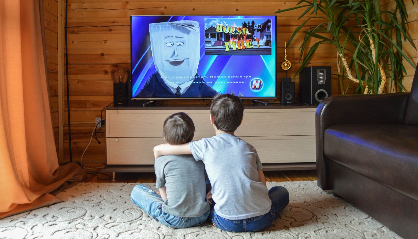 Two brothers watch tv together.