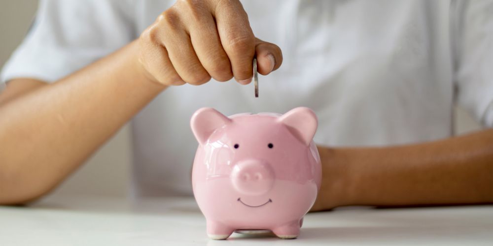Person putting coin into piggy bank