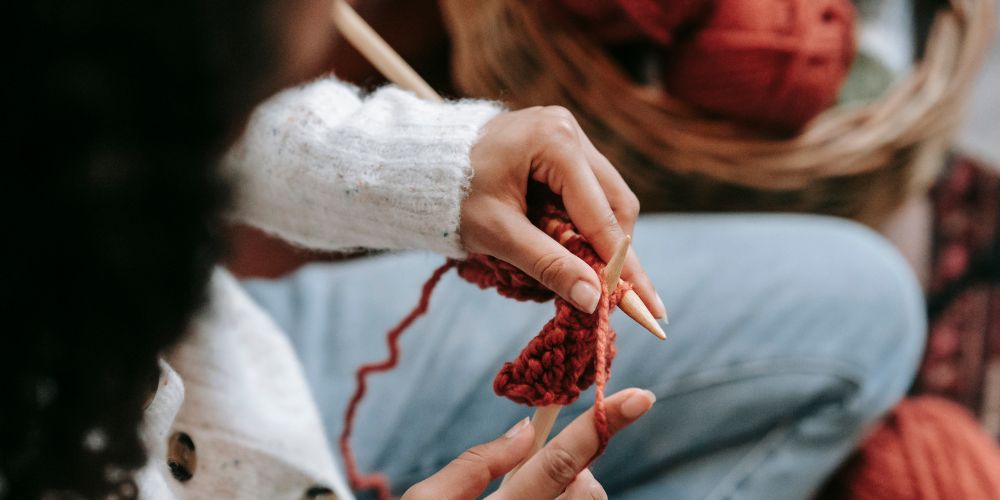 Young woman knitting scarf