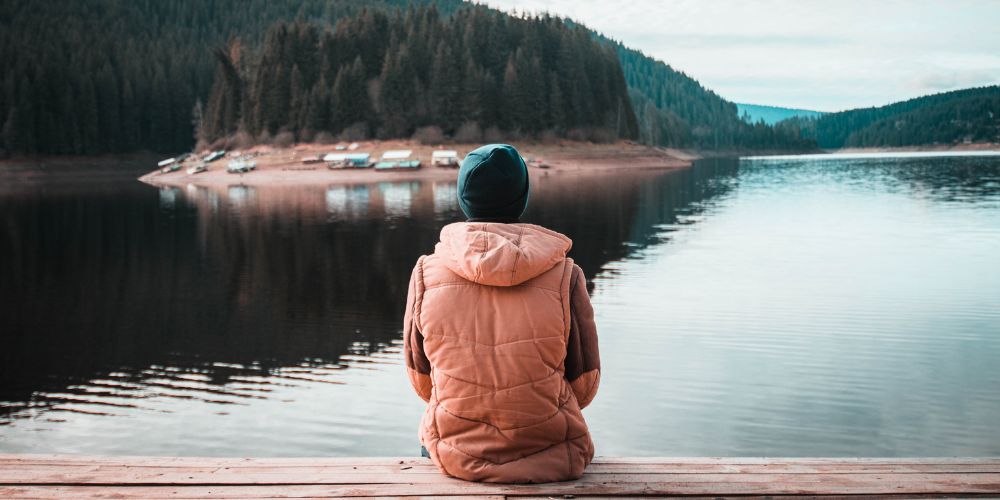 Man sitting looking at lake and surrounding forest