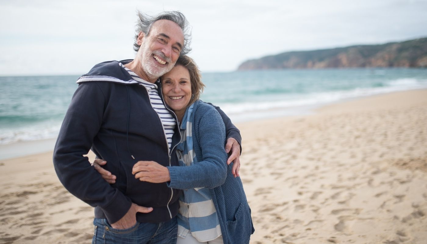 Older couple hugging on beach.