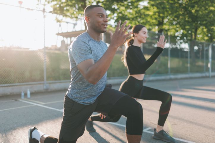 Man and woman outside doing exercises.