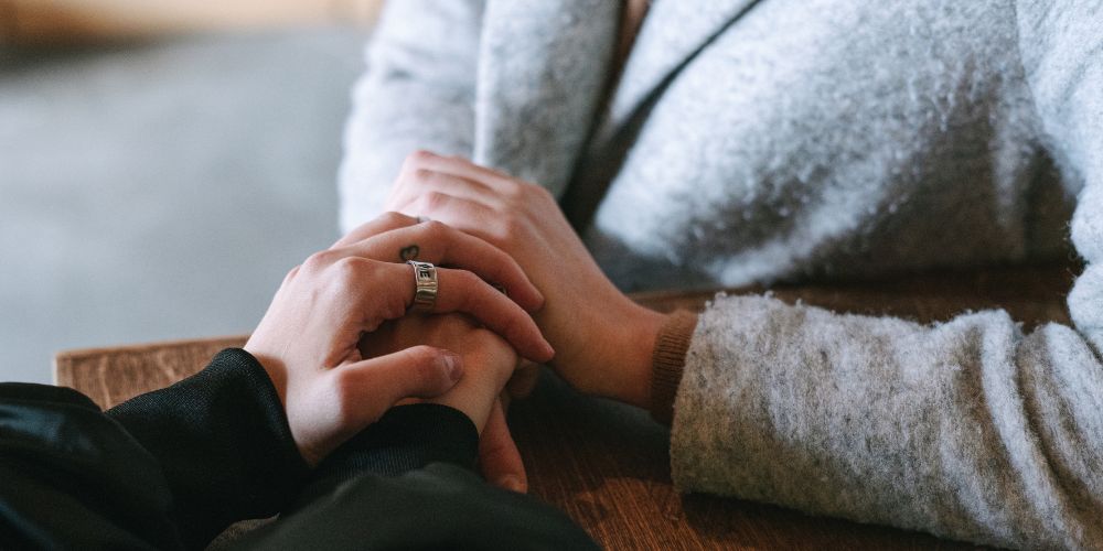 Two people supporting each other holding hands