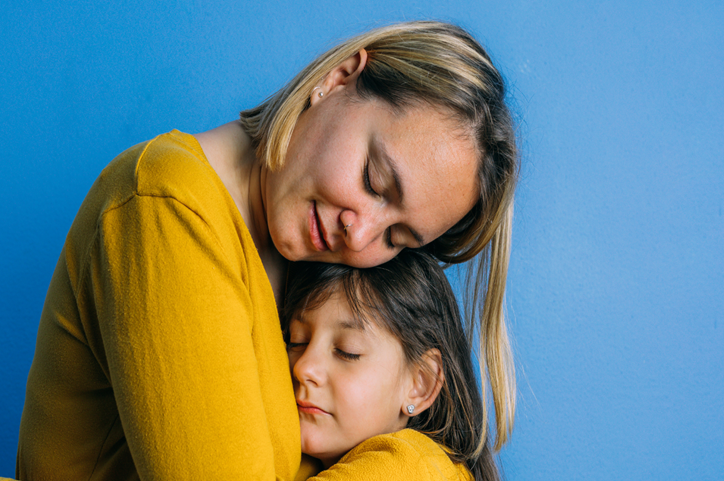 Mother embraces her daughter with a hug.