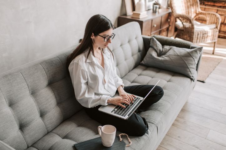 Women sits on her lounge working on her laptop.