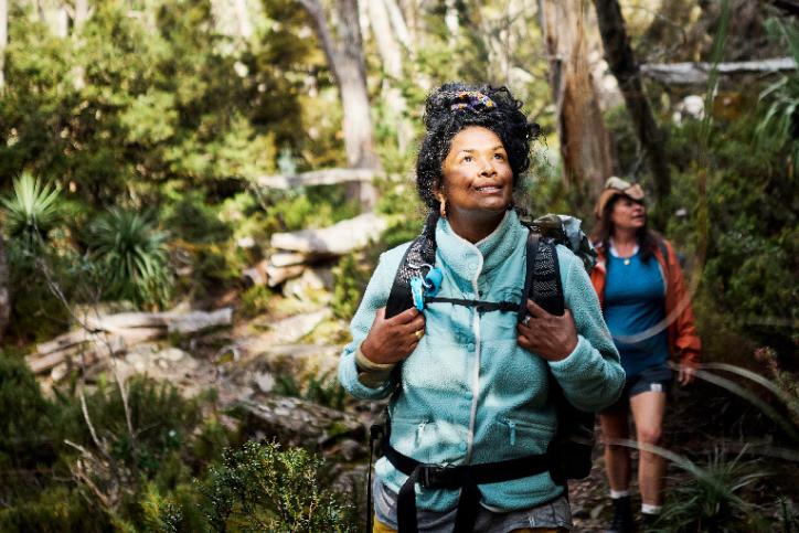 Two women on a hike in the Australian bush, looking up happily at the trees around them