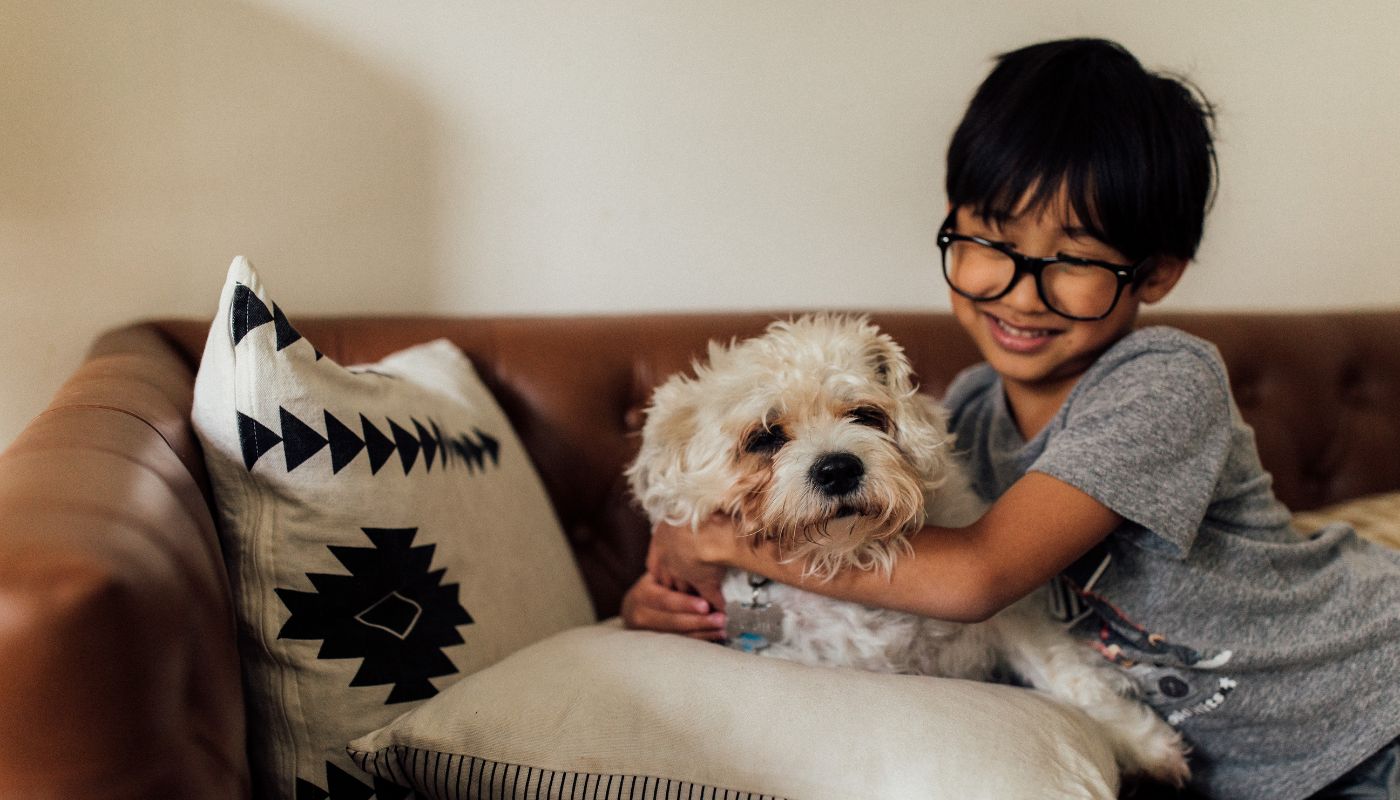 Young boy cuddling his pet dog on the couch