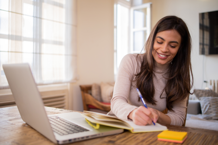 Young woman at her home writing on her journal