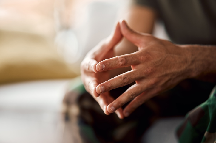 Close up of a man's hands with the tips of his fingers pressed together.