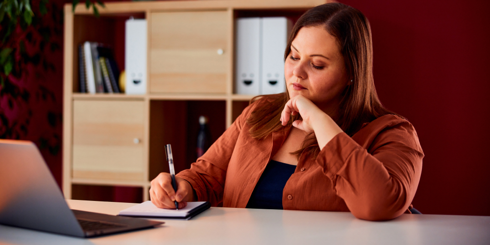 Woman writing on paper as she studies in the library.