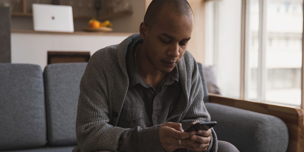 Man sitting on couch using phone
