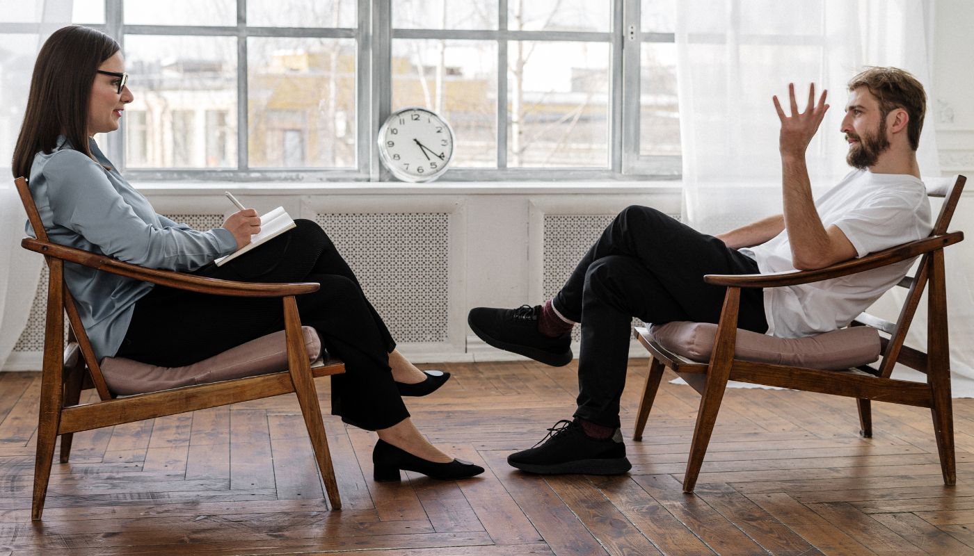Man sits talking to his psychologist in room.