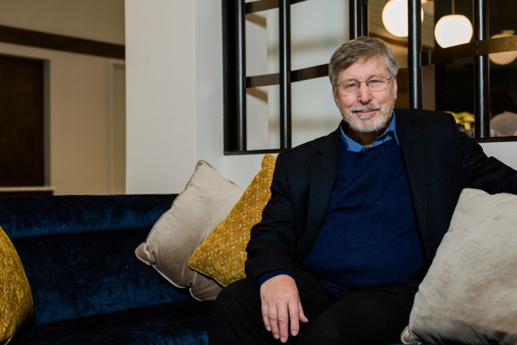 Bessel Van Der Kolk sitting on his couch smiling. 