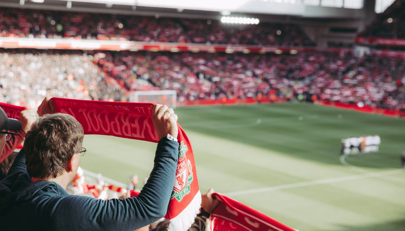 A man watches a football match and holds up his team banner