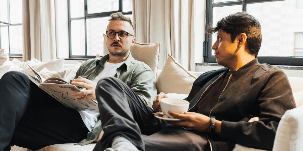 Two male friends sitting chatting on the lounge
