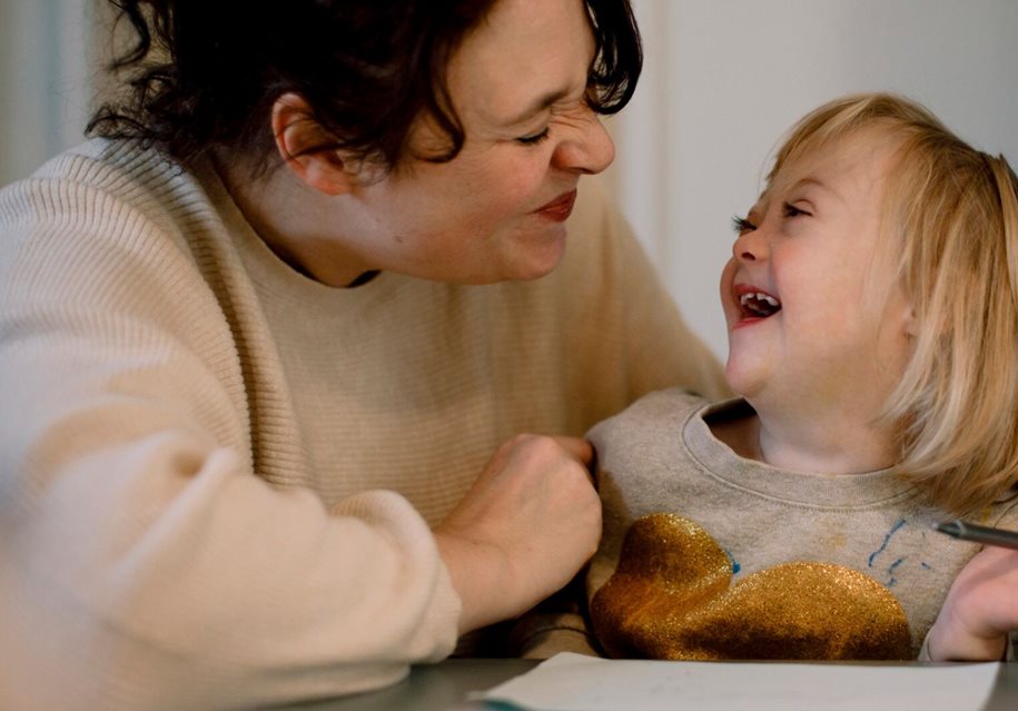 Woman scrunching her face up happily to make a young girl laugh