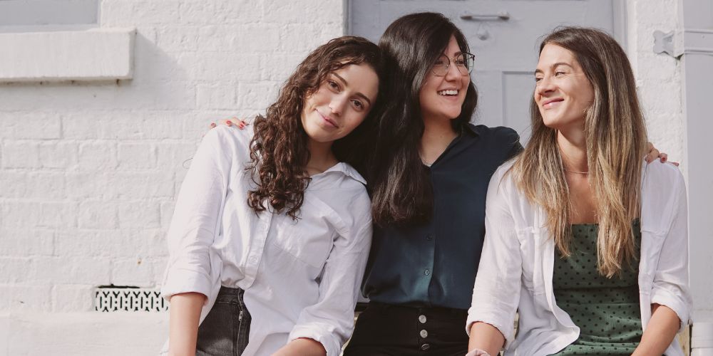 Three young women sitting together smiling