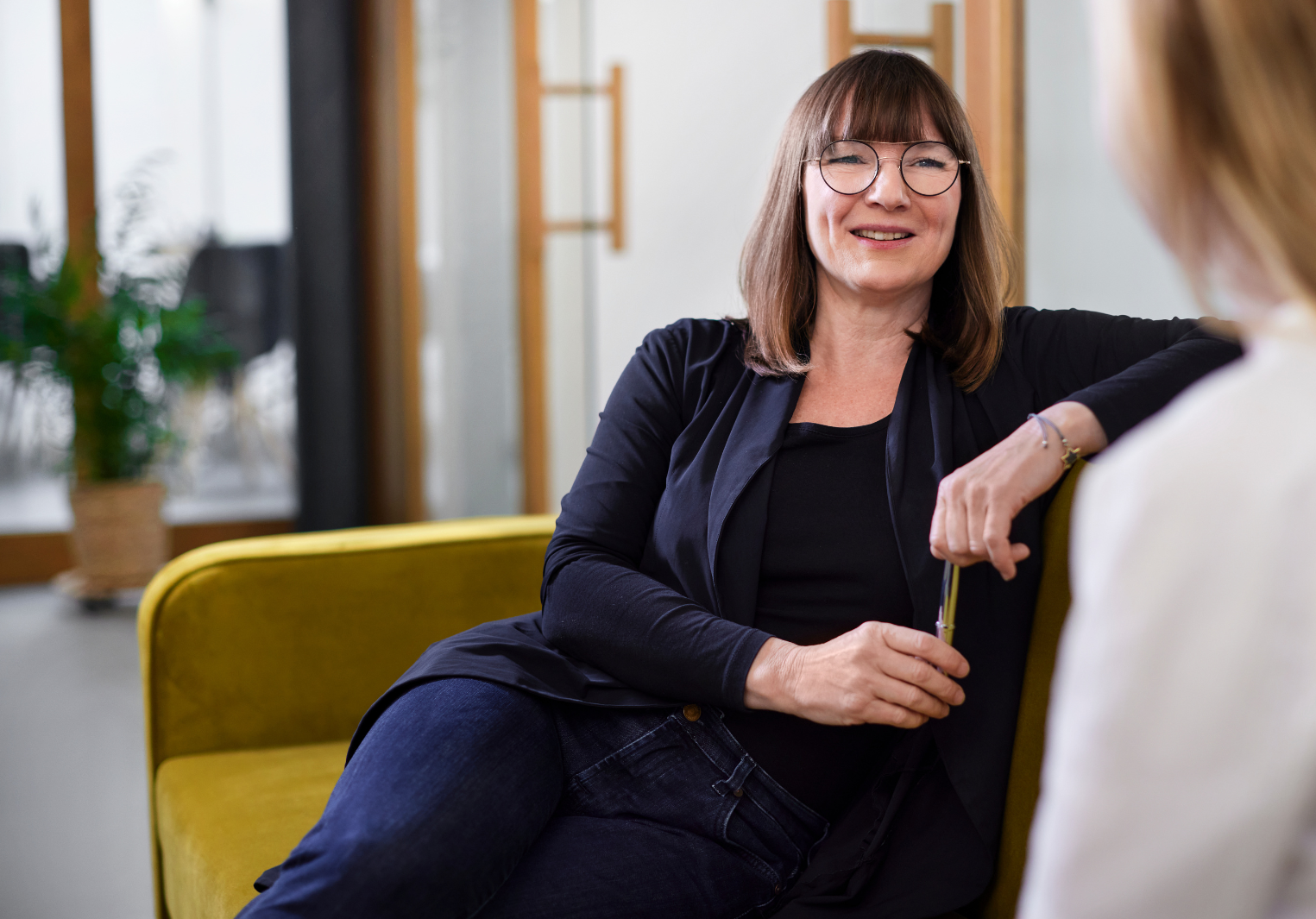 Woman leaning back on a couch smiling at someone off-screen