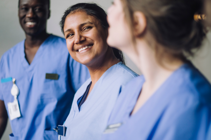 Nurses in their scrubs smiling at each other. 