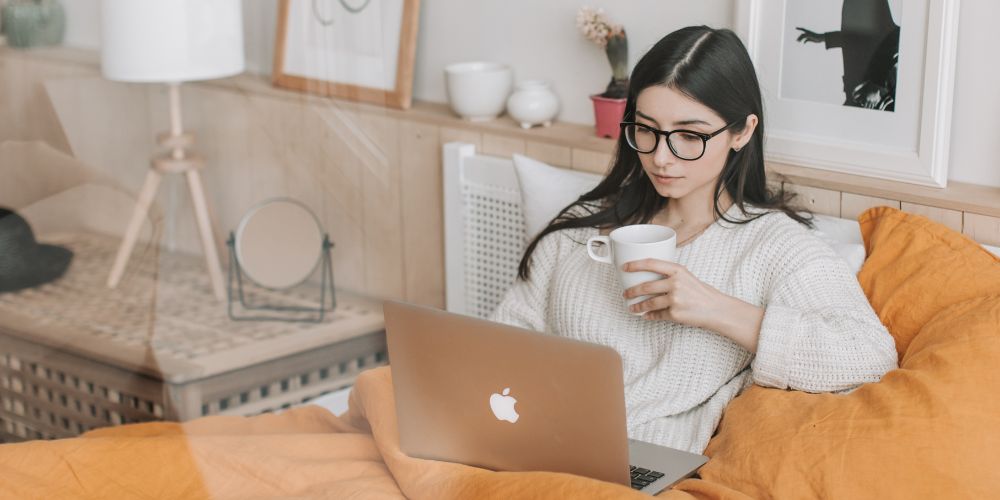 Young woman lying in bed using her computer